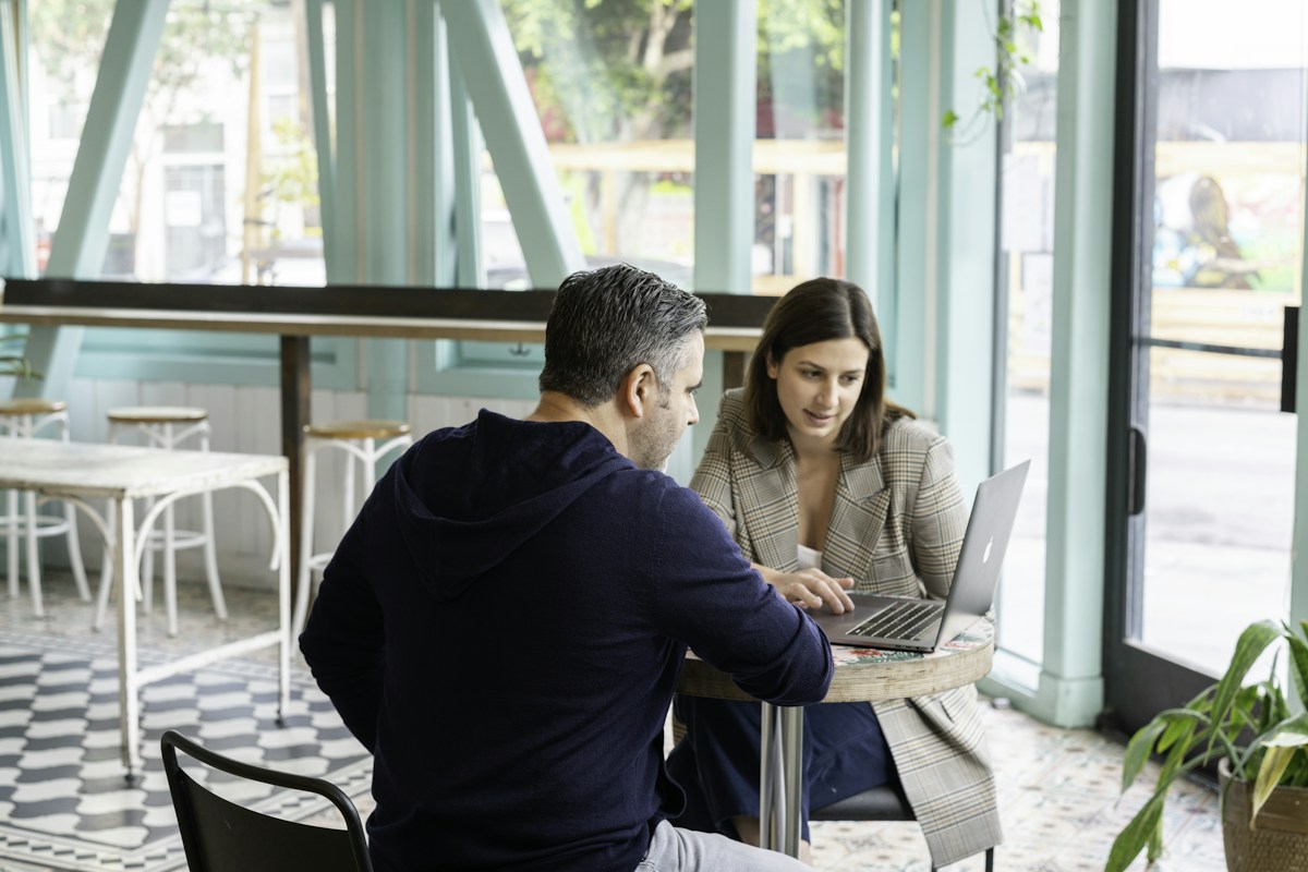 Two people discussing a laptop in a cafe; illustrative stock photograph