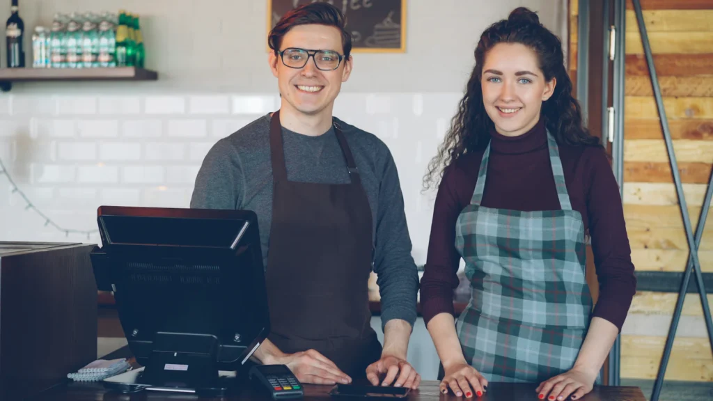 Two staff members smiling at a coffee-house counter